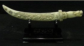 ANTIQUE BONE SWORDS SET: F2018 This is a set of swords, all hand carved from antique bones. It appears light yellow color. The upper one is 32" long and the lower one is 28". Both sitting on a wooded rack. Dragon or flowers a
