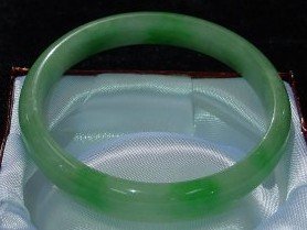 BURMESE JADEITE ROUND BRACELET: SKU: JP52is bracelet is made from one solid piece of BURMESE JADEITE. All natural color. It appears light green with some spots dark green. It is transparent. Wearing jade bracelet is believed to impr