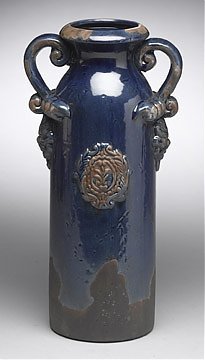 Vase: Code: 10804-BL Distressed blue painted crackle finish earthenware with unfinished brown base. Raised crest-like design on front and back and lion head design at base of handles. Top of inside is finis