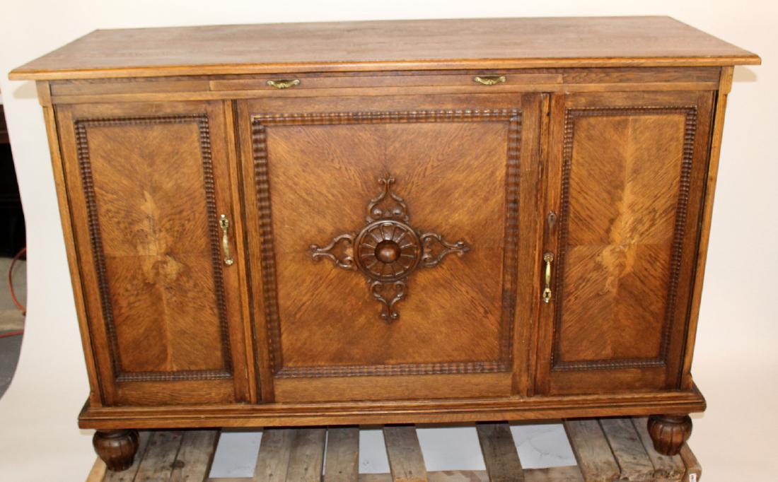3 door sideboard with center medallion: 3 door sideboard with center medallion. In oak. Back is open and would make an excellent front bar. Early- mid 20th century. 41 1/2"h x 63 1/4"w x 25 1/2"d