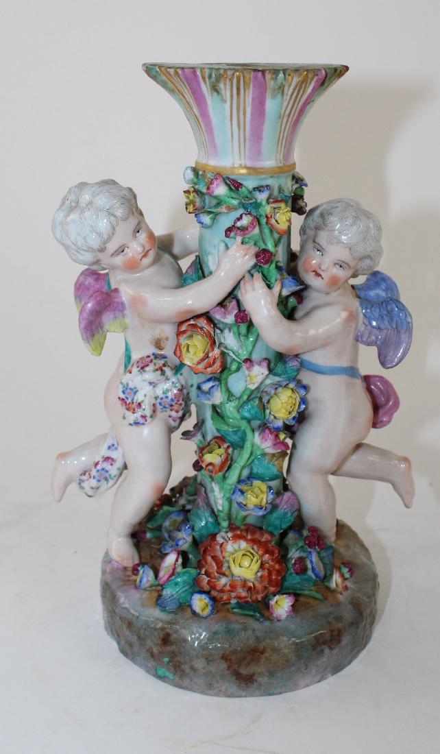 German porcelain figurine with cherubs: German porcelain figurine with cherubs. Similar crossed swords mark but not believed to be Meissen. 9 1/2"h x 6"w