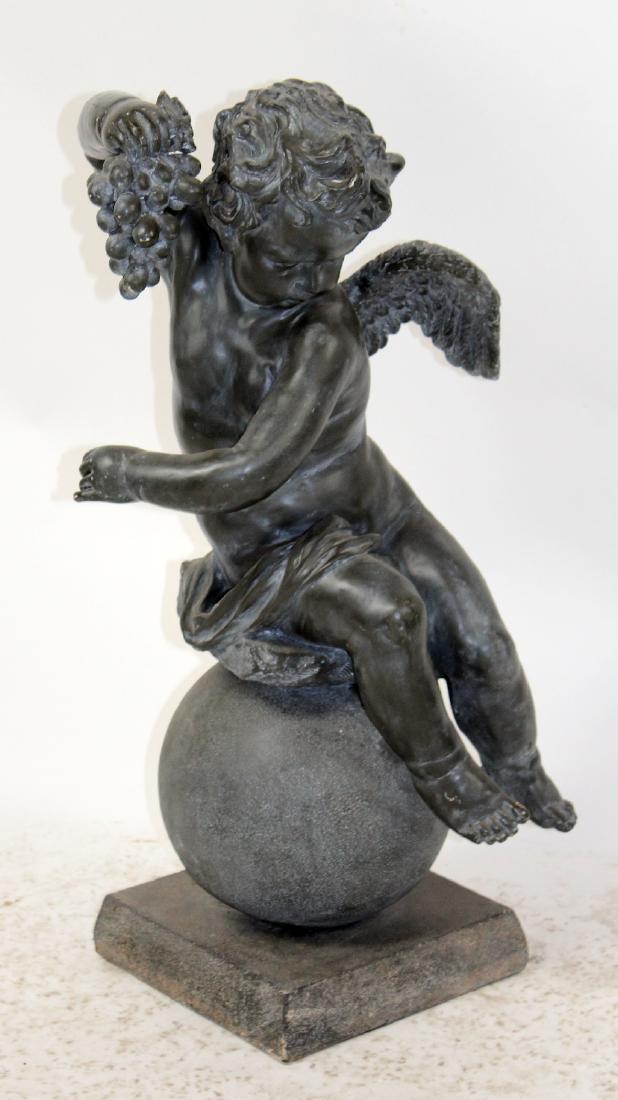 Cast sculpture of cherub on ball