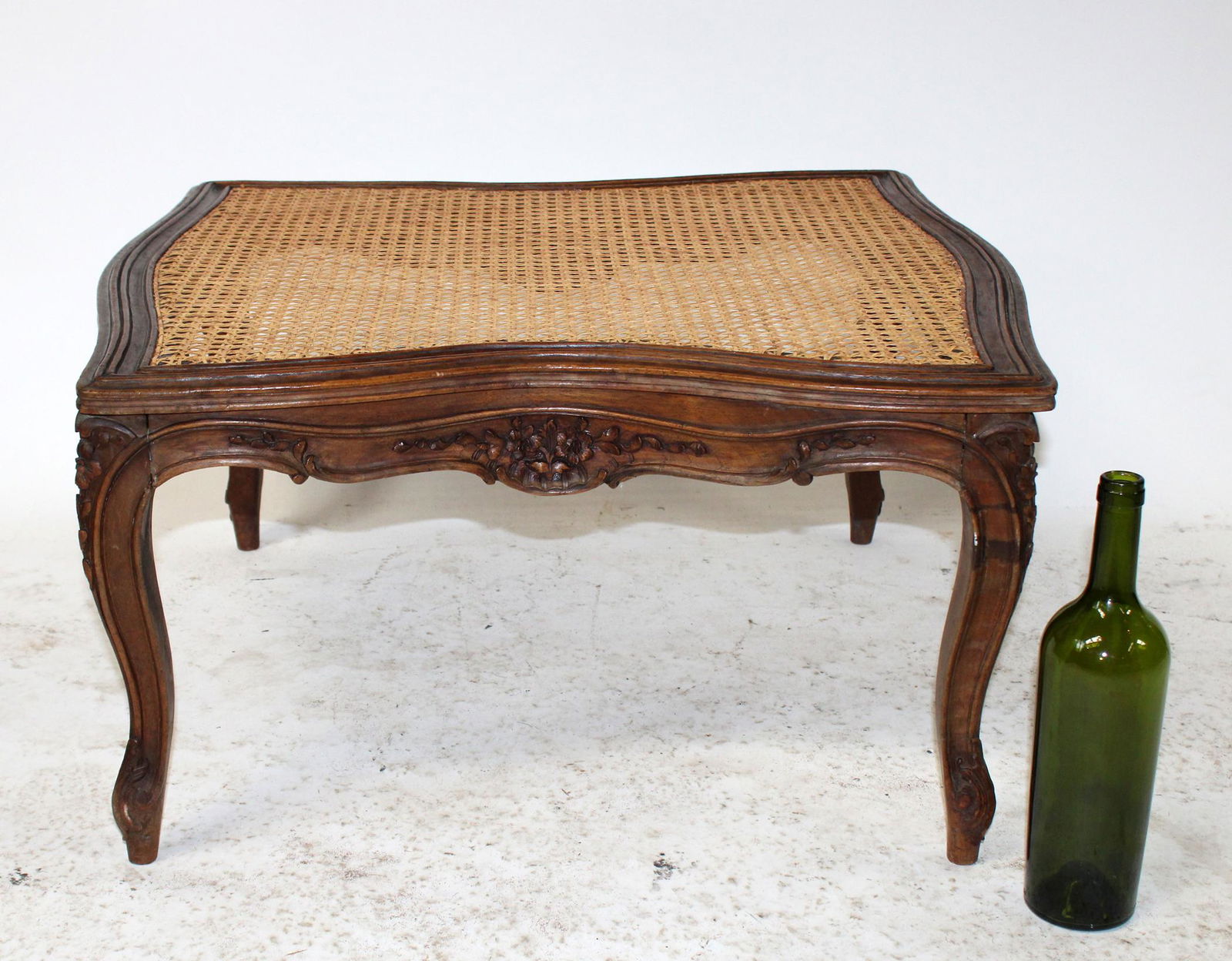 French Louis XV walnut ottoman footstool: French Louis XV walnut ottoman footstool with caned top and carved apron. Early 20th century. 14 1/4"h x 27"w x 25"d