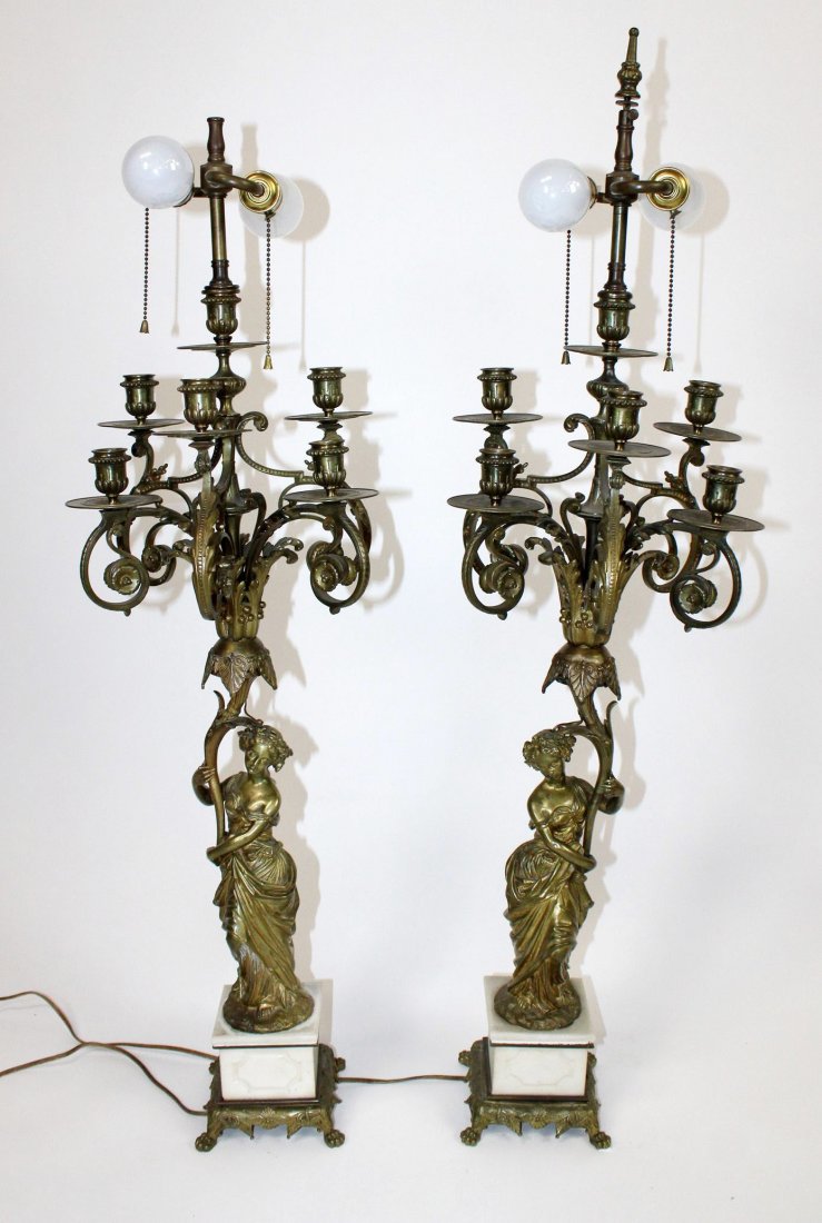Pair of antique French bronze figural candelabra: Pair of antique French bronze figural candelabra converted into lamps on white marble bases. 37 1/2"h x 11 1/2"w x 9"d