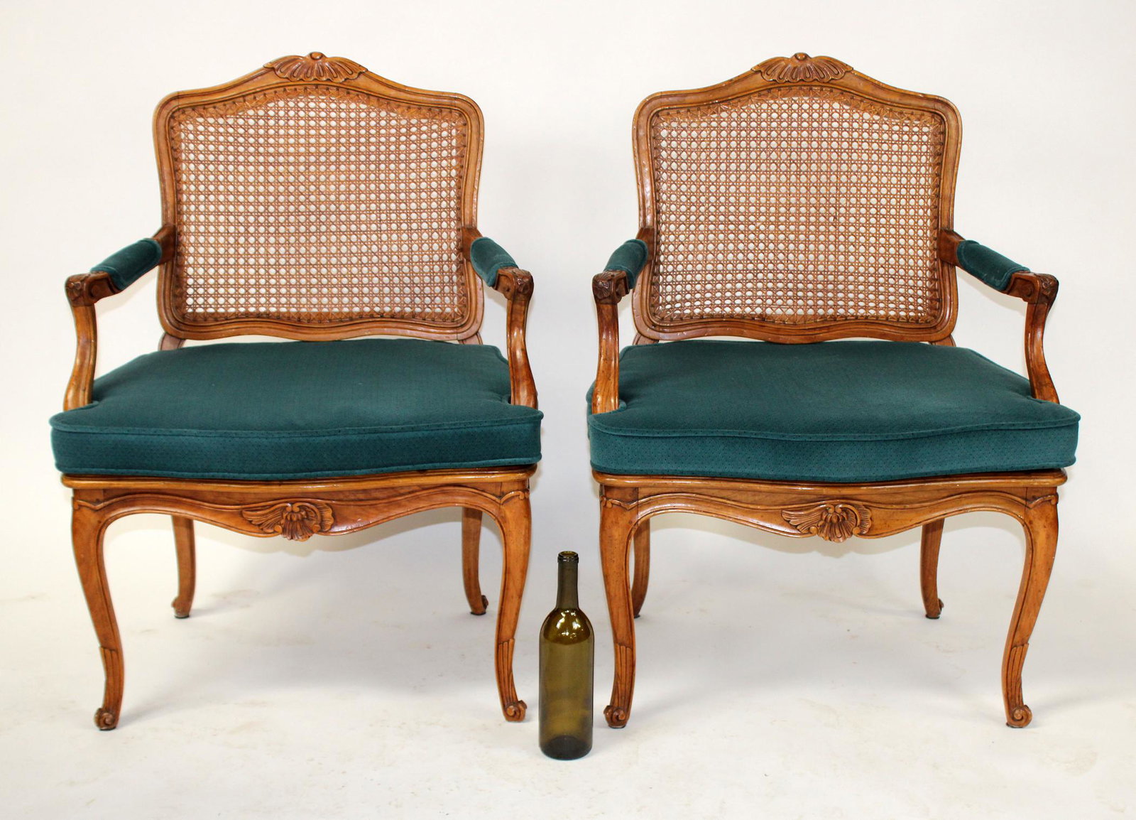 Pair of Louis XV style caned armchairs: Pair of Louis XV style armchairs in carved walnut with cane back and seats. Custom upholstered seat cushion. Mid 20th century. 36 1/4"h x 26 1/4"w x 23"d, seat height 15 1/2"h