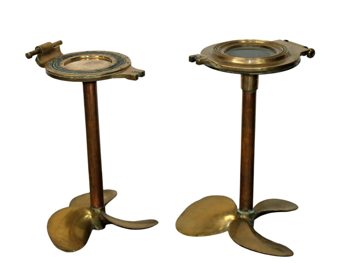 Set of 2 French bronze propeller base side tables: Set of 2 French bronze propeller base side tables with porthole cover tops. Early 20th century. 24 1/2"h x 17 1/2"w x 16"d