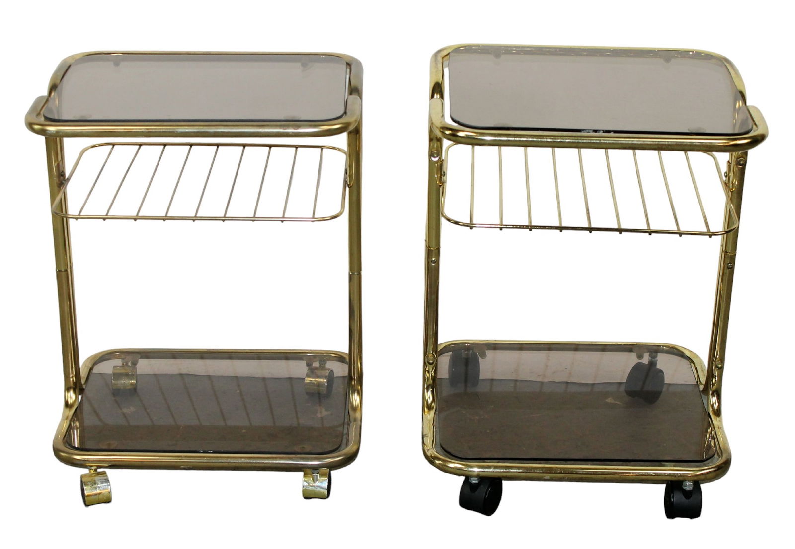 Companion pair of French brass & smokey glass 2-tier rolling bar carts: Companion pair of French brass & smokey glass 2-tier rolling bar carts. Circa 1960's. Larger one: 21 1/4"h x 16 1/8"w x 14 1/8"d. Smaller one: 20 5/8"h x 16 1/8"w x 12 7/8"d