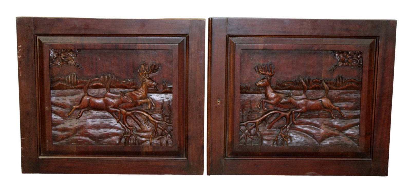 Pair of carved mahogany panels with deer: Pair of carved mahogany panels with deer in relief. 21st century. 22 1/4"h x 25 3/4"w.