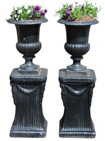 Pair of cast iron urns atop cast pedestals painted black