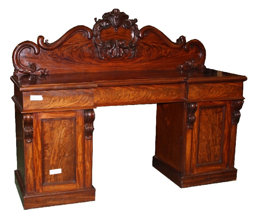 Victorian pedestal sideboard in flame mahogany: with shaped and carved backsplash. Interior features a cellarette. Circa 1860. 59 1/4"h x 74 1/4"l x 26 1/4"d