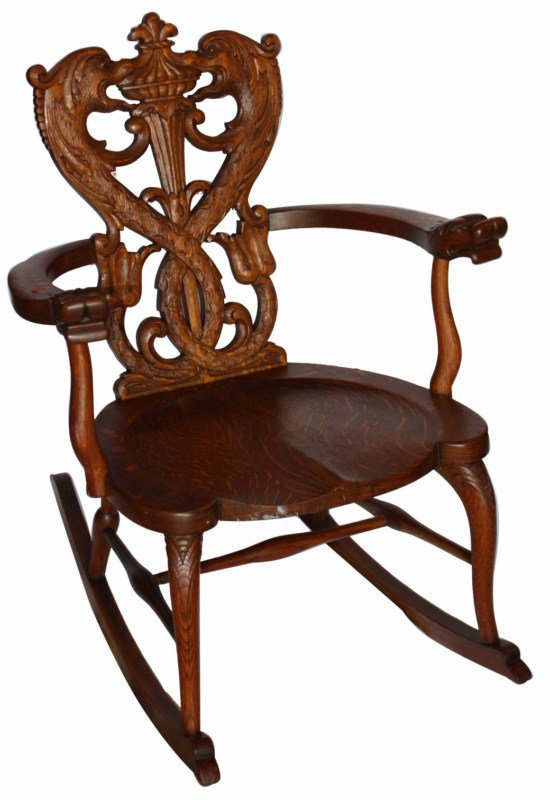 American heavily carved oak rocking chair: Back of chair consists of 2 intertwined mythological dolphins flanking a center torch. 26"w x 34"h x 19"d