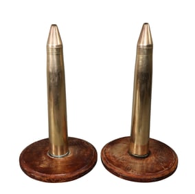 Pair of brass artillery shells mounted as sculpture on wooden stands