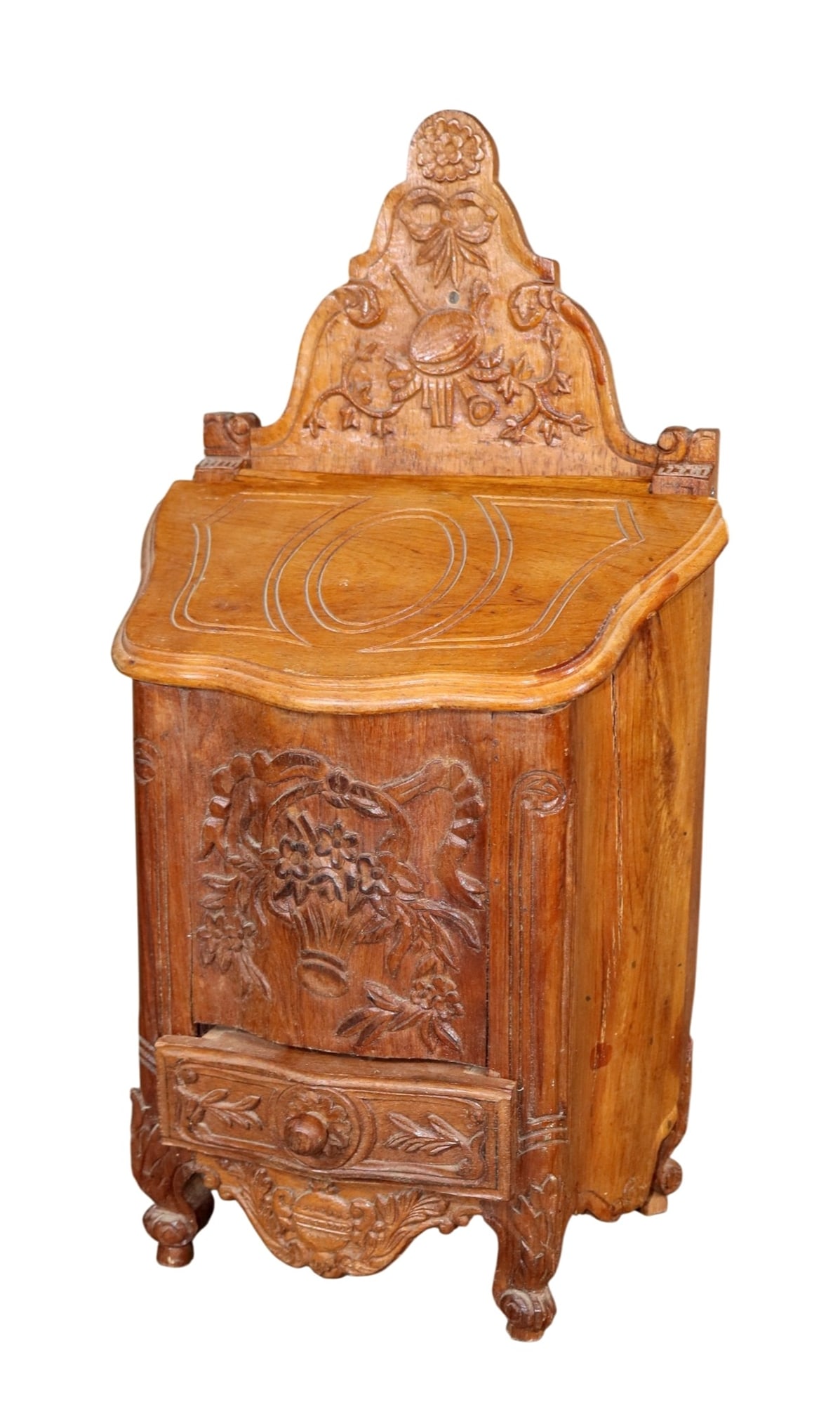 French Provincial carved walnut salt box with relief carved floral and ribbon motifs: French Provincial carved walnut salt box with relief carved floral and ribbon motifs. Early 20th century. 19 1/4"h x 9 1/2"w x 6"d Weight: 7lbs