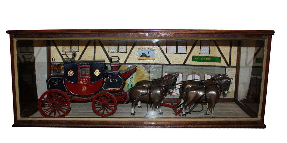 Model of a British Stagecoach mail carrier with horses: In a custom glass and wood display box. Painted wooden model with a painted backdrop. 15"h x 39 3/4"l x 14 1/2"d