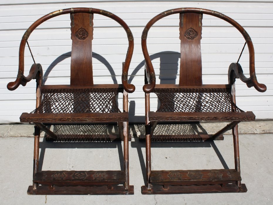 Pair of Chinese huanghuali horseshoe folding chairs: Back is carved with dragon & phoenix and each is balusted with ornamental bronze. 40"h x 27 1/8"l x 25"d