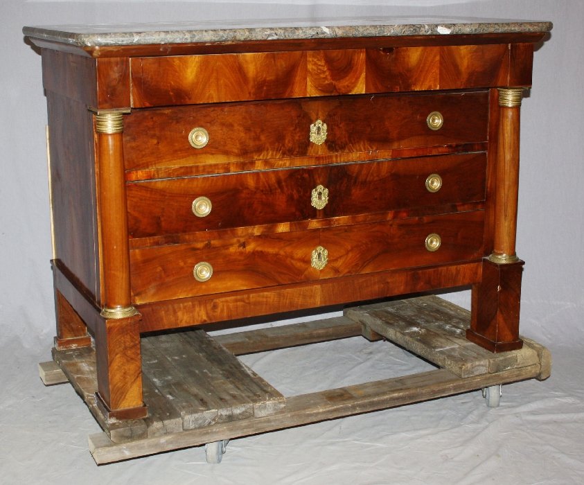 French Empire commode in burl walnut: Turned columns with bronze capitals flank each side. Drawers are ornamented with polished bronze escutcheons and drawer pulls. Circa 1810. 35 1/4"h x 49 1/2"w x 24 1/8"d