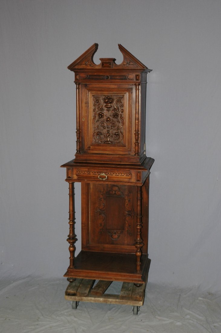 French Classical wine cabinet in carved walnut: On turned legs. Center door has relief carvings of fruited urn and foliate detail. 19th century. 74"h x 26 1/4"w x 20"d