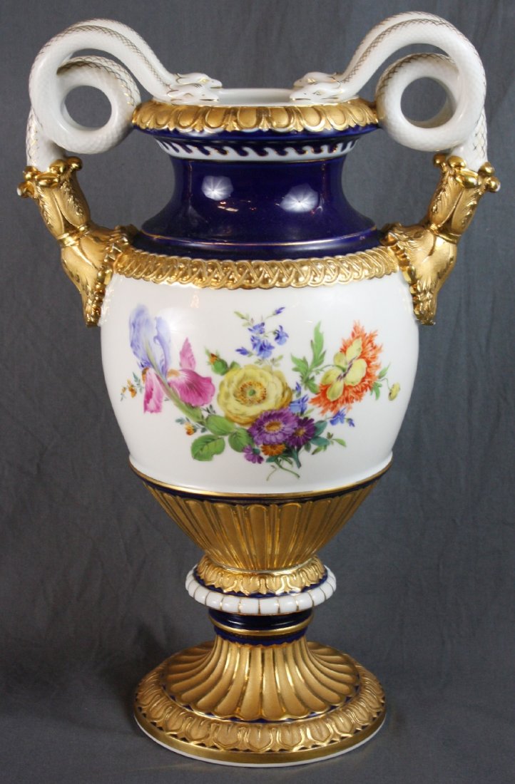 Meissen porcelain double handled snake vase: Hand painted flower decoration on a white background with a cobalt neck. Vase is further accented with gold. Handles are in the form of sculptured snakes. Marked with blue underglaze crossed swords an