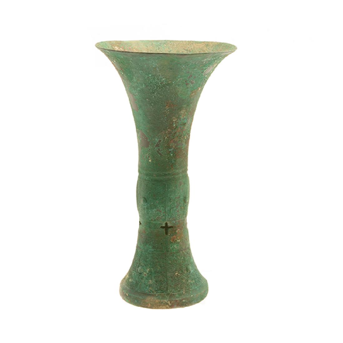 Archaic Bronze Gu: Archaic Bronze Gu Featuring an elongated trumpet neck rising from an ovoid convex node with two vertical projecting flanges at opposing sides above four cross-shaped openings and a flaring foot. Heigh