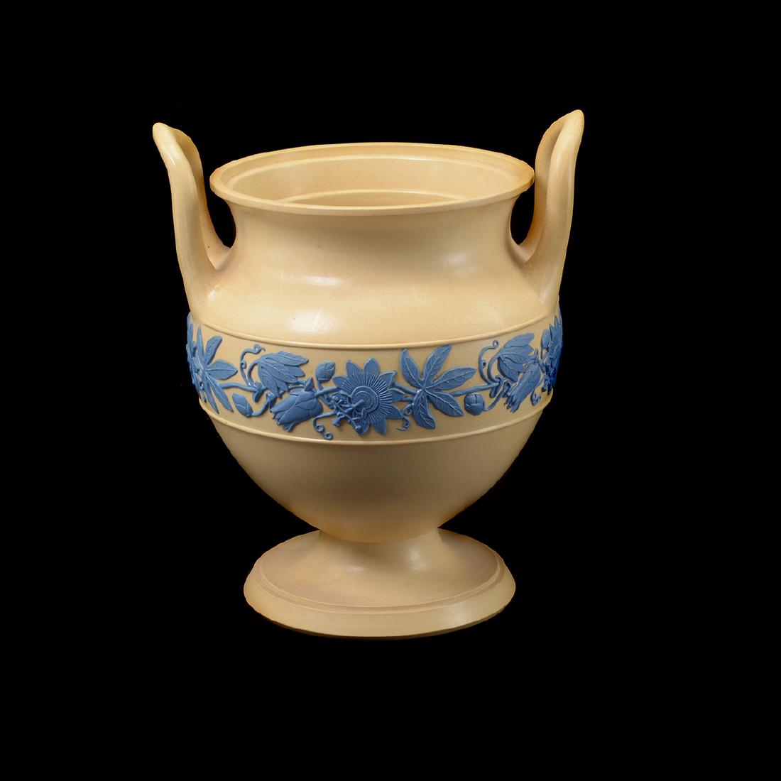 Wedgwood Yellow and Blue Urn: Wedgwood Yellow and Blue Urn. Yellow urn form with loop handles, and relief blue floral and leaf garland surrounding. {Dimensions: 9 1/2 x 8 x 7 1/2 inches.} (One crack to garland leaf.)