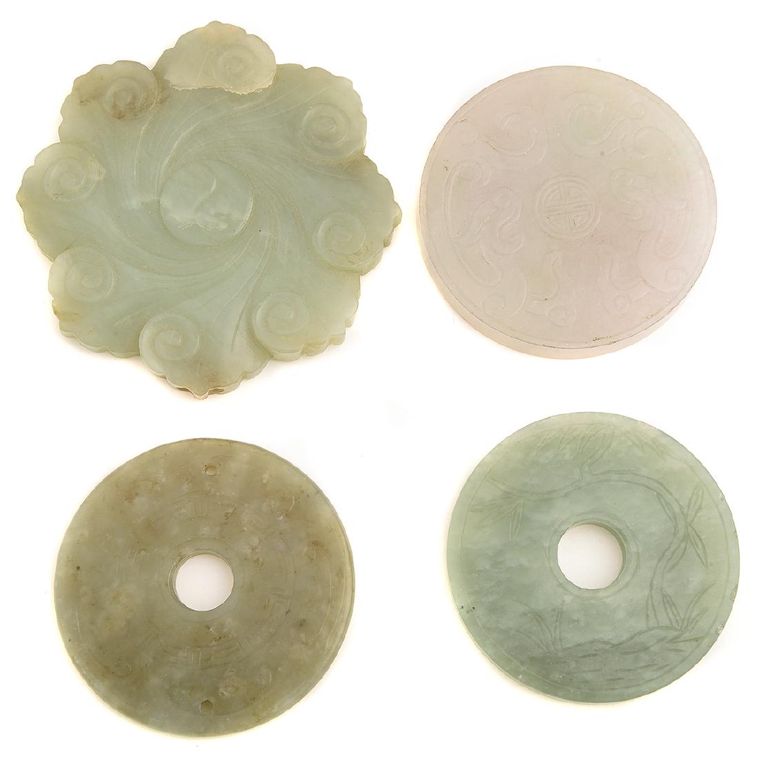 Collection of Four Celadon Jade Discs.: Collection of Four Celadon Jade Discs. Including one carved celadon jade flower, the obverse depicting yin and yang in the center of wind and measuring approximately 70 x 75 x 7 mm; one carved and pie