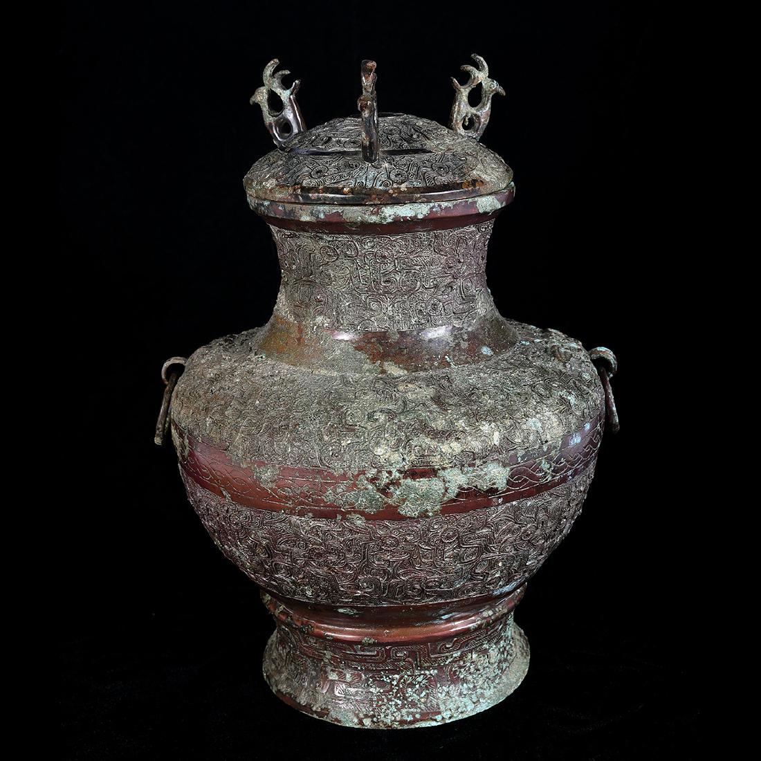 Chinese Archaistic Bronze Vessel with Cover: Chinese Archaistic Bronze Vessel with Cover. The body cast with stylised dragons, with two looped rings suspended from chilong head on the shoulder, the cover with three phoenix. {Height: 12 1/2 inche
