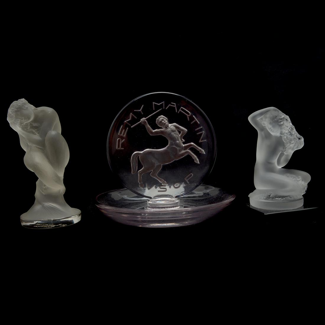 Two Lalique Items With One Additional.: Two Lalique Items With One Additional. Comprising a seated sleeping female nude, and a female nude with flowers. Additional piece is a Remy Martin V.S.O.P. ring holder with centaur. Sleeping female ma