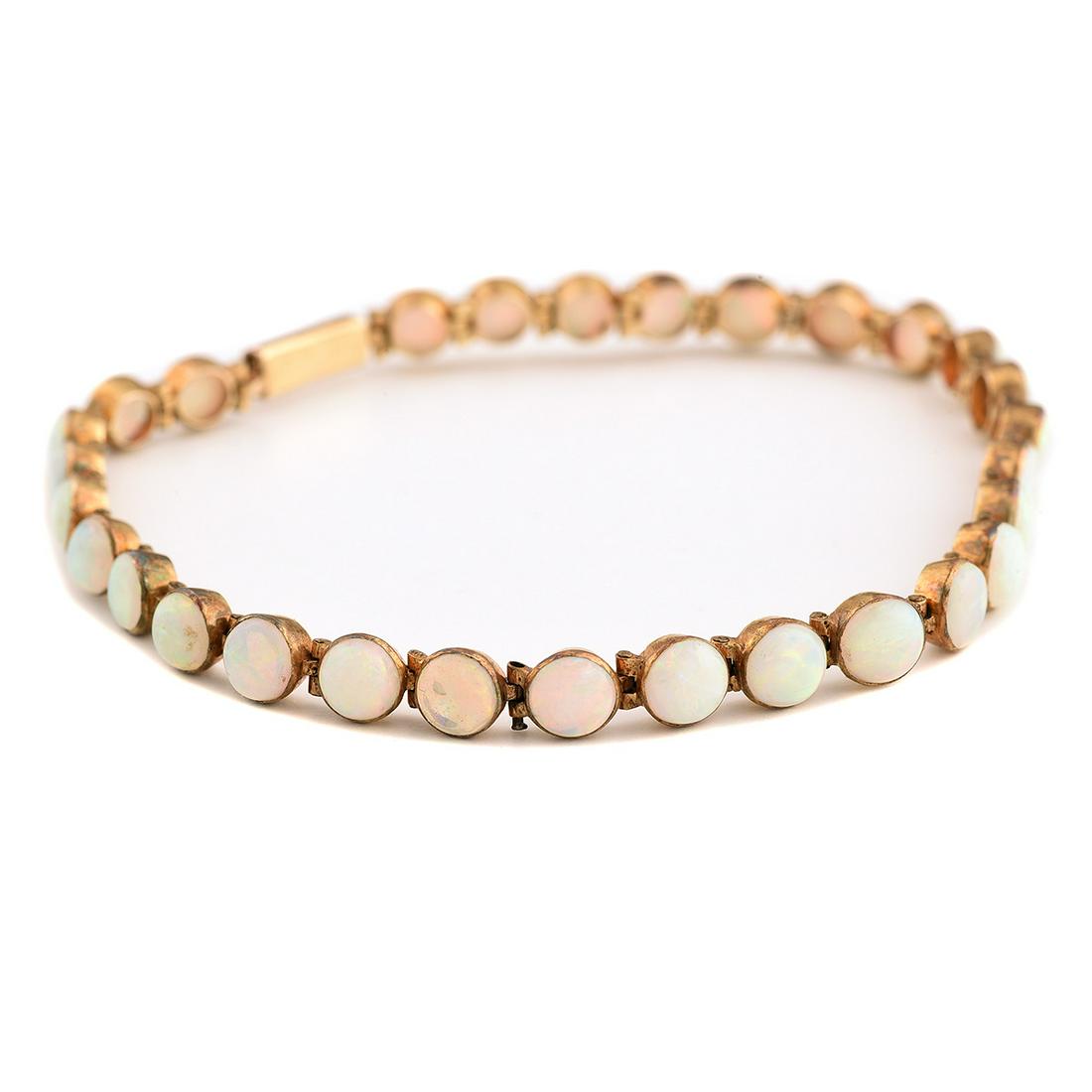 Opal, 8k Yellow Gold Bracelet.: Opal, 8k Yellow Gold Bracelet. Composed of twenty-nine round shaped opal cabochons measuring approximately 5 mm to 4.7 mm, set in an 8k yellow gold mounting, completed by a tongue and groove clasp, fo