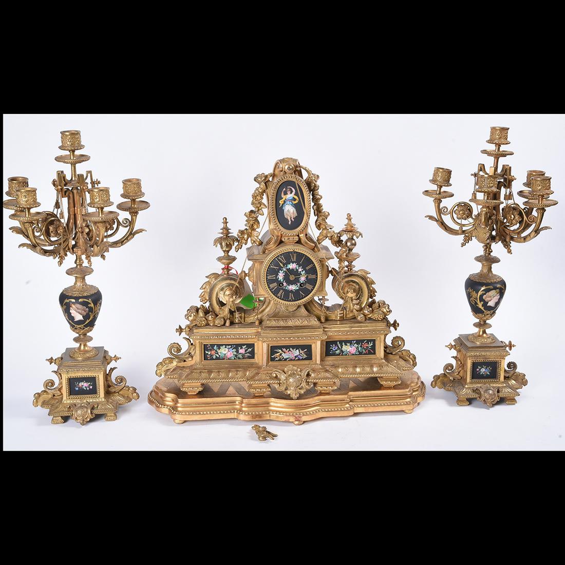 French Romanesque Ormolu and Porcelain Three Piece: French Romanesque Ormolu and Porcelain Three Piece Mantel Clock Garniture. Clockworks by Morel Â· Bordeaux. Comprising a mantel clock inset with matte black porcelain plaques painted with trophies i