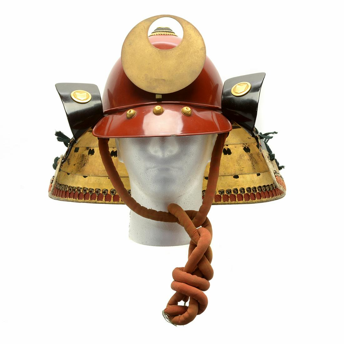 Japanese Kabuto Helmet, Edo Period: Japanese Kabuto Helmet. Composed of red and gold lacquered crimson, with gold plated tamabuchi, the shikoro of two black-lacquered steel plates, visor with three gold plated buttons. Edo Period. {Diam