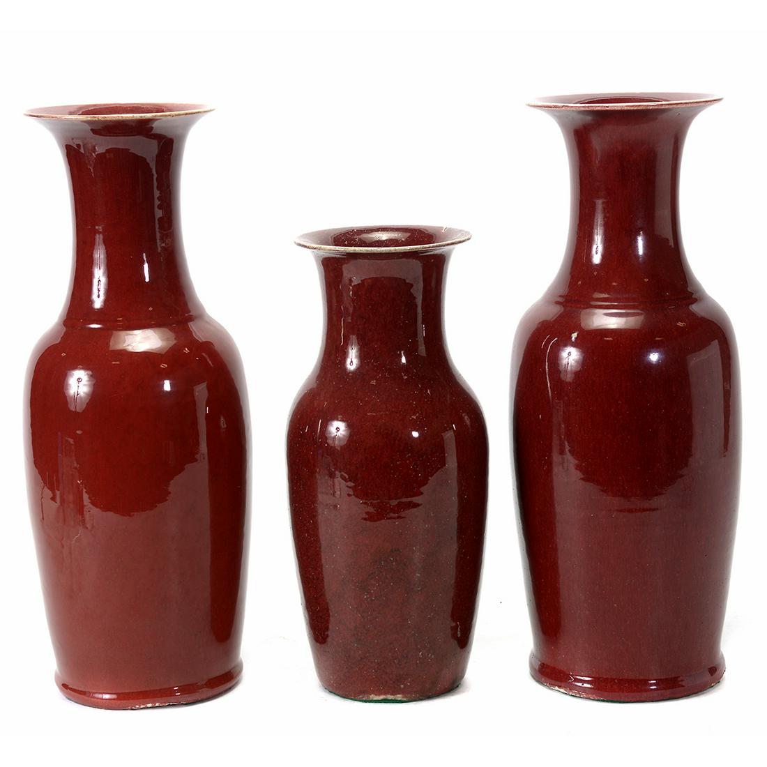 Three Chinese Ox Blood Baluster Vases: Three Chinese Ox Blood Baluster Vases. Comprising three similar shape ox blood vases, all with flared mouths. {Tallest: 22 1/2 inches (57.2 cm)}. [Restore, chips to the bases].