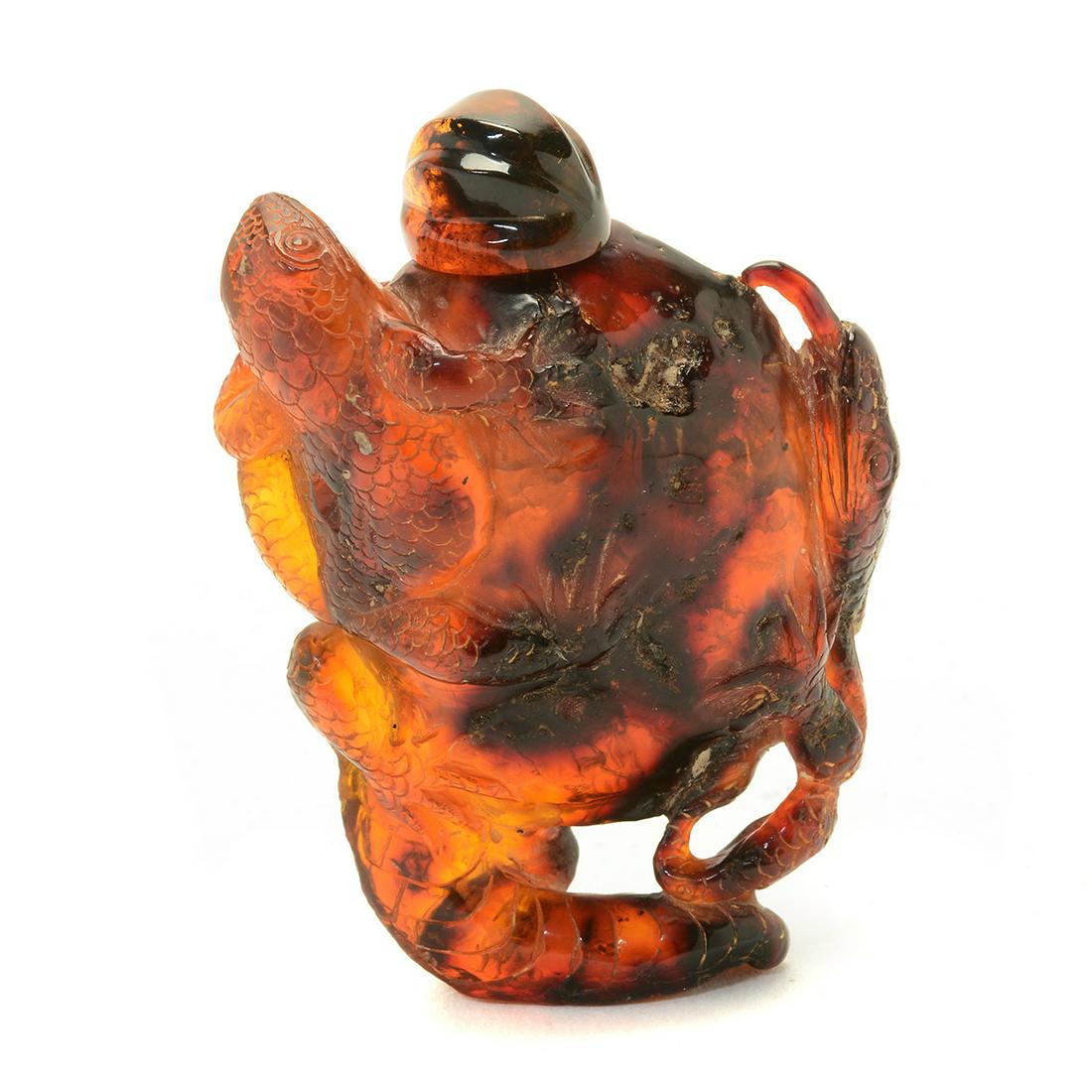 Carved Amber Snuff Bottle.: Carved Amber Snuff Bottle. The translucent amber body with rounded shoulders and flat lip, the sides surrounded by a lizard and frog finely incised with scaly patterns. {Approximate height: 3 inches (