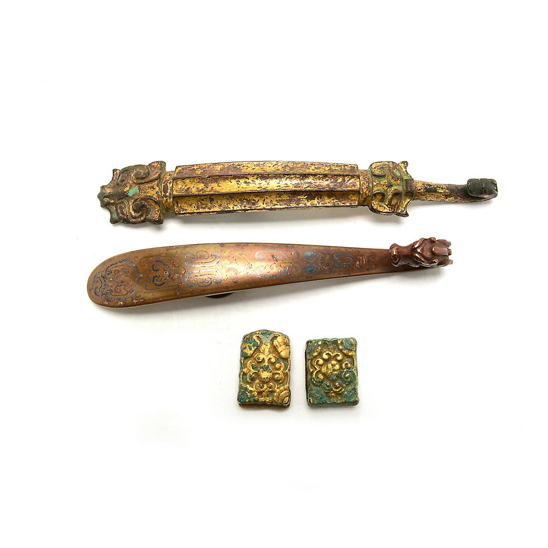 Group of Two Bronze Belt Hooks and Two Ornaments.: Group of Two Bronze Belt Hooks and Two Ornaments. Comprising a gilt bronze dragon and mythical beast ridged belt hook; a bronze dragon belt hook; and a pair of gilt bronze foliate relief ornaments. {L