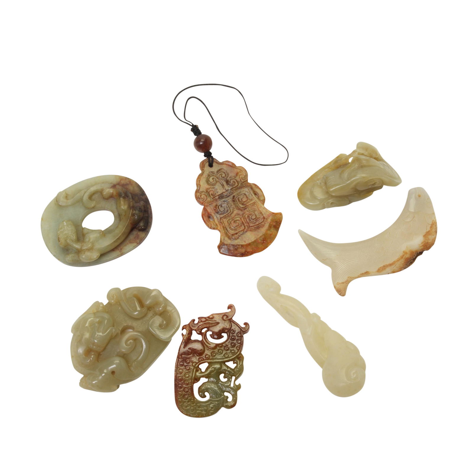 Group of Seven Carved Jade Pendants.: Group of Seven Carved Jade Pendants. Including a mutton fat jade lingzhi spray; a mutton fat jade fish with a large area of opaque russet-tinged calcification; a celadon jade crane group with small ar