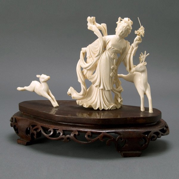 Chinese Carved Ivory Lady and Deer w/ Stand, 20th : Chinese Carved Ivory Dancer with Deer and Wood Stand, 20th Century. Female form walks with flowing robes while two deer bound beside her, figures fixed to stand of open work scrolls. {Height 8 1/2 inc