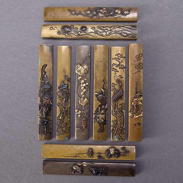 Ten Mixed Metal Kozukas: Ten Mixed Metal Kozukas, decorated with Buddhist figures and landscape scenes with animals, six signed verso {Height 4 inches}