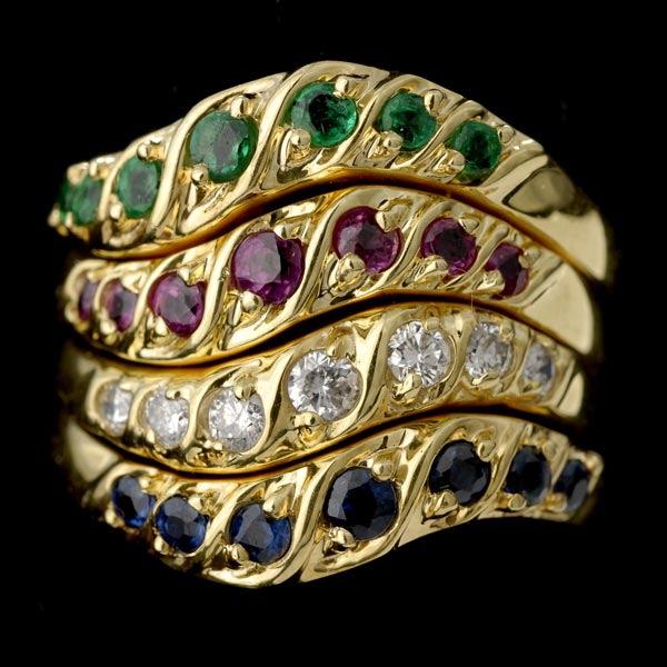COLLECTION OF FOUR MULTI-STONE, 14K GOLD RINGS: COLLECTION OF FOUR EMERALD, SAPPHIRE, RUBY, DIAMOND, 14K YELLOW GOLD RINGS. Including four 14k yellow gold stackable wave mountings, each with seven round-cut stones; one with emeralds weighing a tota