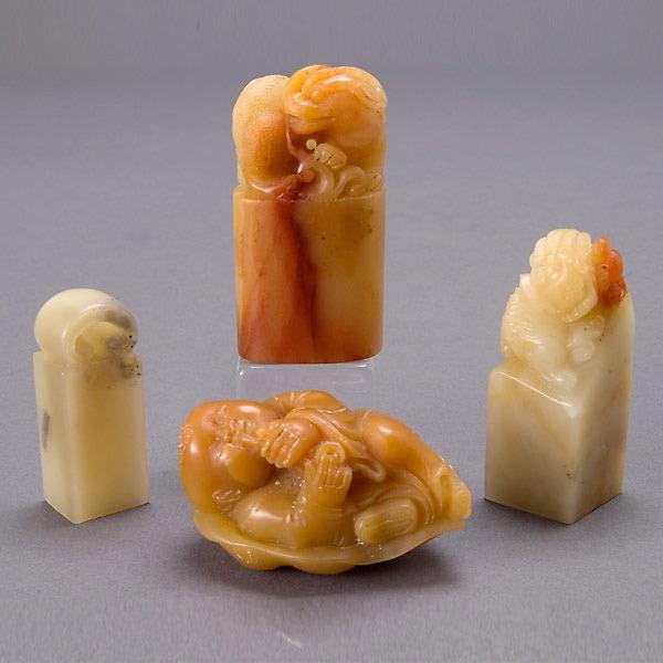 A Group of Four Small Soapstone Carvings: A Group of Four Small Soapstone Carvings, including three seals of a dragon, lion and ruyi head, and one small carving depicting a boy on a lotus leaf {Tallest 2 inches}
