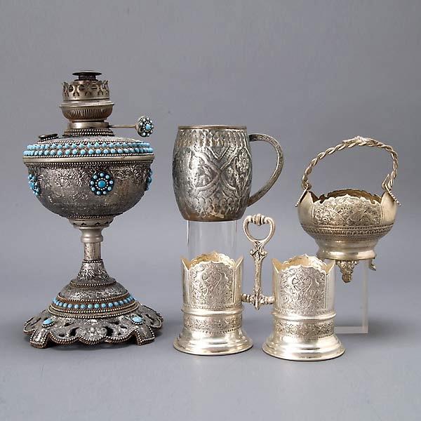 Four Middle Eastern Metal Wares: Four Middle Eastern Metal Wares: an oil lamp with blue stone decoration; a mug; a decanter stand; and a basket {Height of lamp 12 1/2 inches}