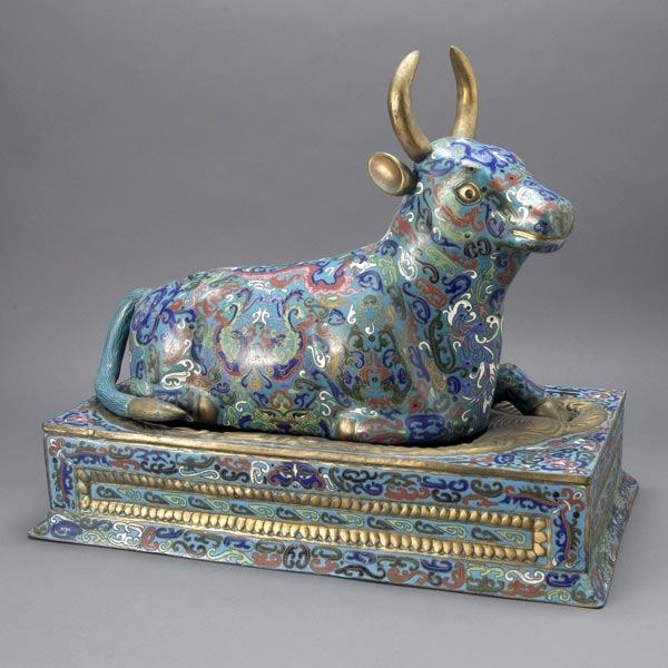 A Large Cloisonné Enameled Recumbent Buffalo: A Large Cloisonné Enameled Recumbent Buffalo, resting upon a matching rectangular base surrounded by a border of swirling gilt waves {Length 23 inches}