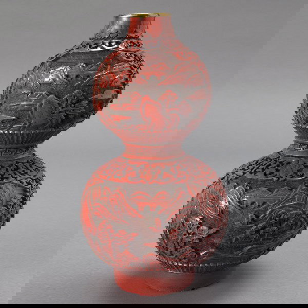 A Cinnabar Lacquered Double-Gourd Vase: A Cinnabar Lacquered Double-Gourd Vase, decorated with four landscape reserves surrounded by scrolling lotus flowers, gilt rim {Height 8 1/2 inches} [Cracks]