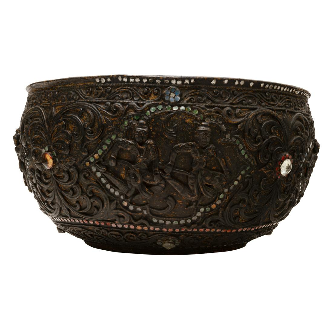 A Large Burmese Black Dry Lacquered Inlaid Bowl: A Large Burmese Black Dry Lacquered Inlaid Bowl. The large circular form bowl is carved and decorated with six shaped cartouches depicting Jakata warriors in combat scenes between flowing scrolling ar