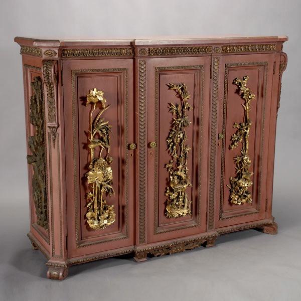 A Chinese Export Faux Cinnabar Three Door Cabinet: A Chinese Export Faux Cinnabar Painted Three Door Cabinet Mounted with Gilt and Ebonized Figural Carvings, Provenance: Gumps {Dimensions 52 1/2 x 66 x 21 3/4 inches} [KEY, overall wear, minor chips an