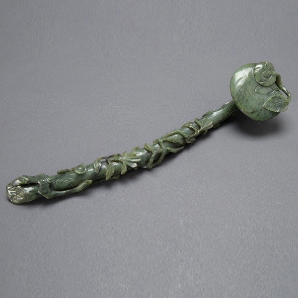 A Green Jade Ruyi Scepter, Qing Dynasty: A Green Jade Ruyi Scepter, In the form of an elegantly curved branch with rounded head, flower blossoms and lingzhi issuing from smooth leafy twigs encircling the body and terminating upon the rounded