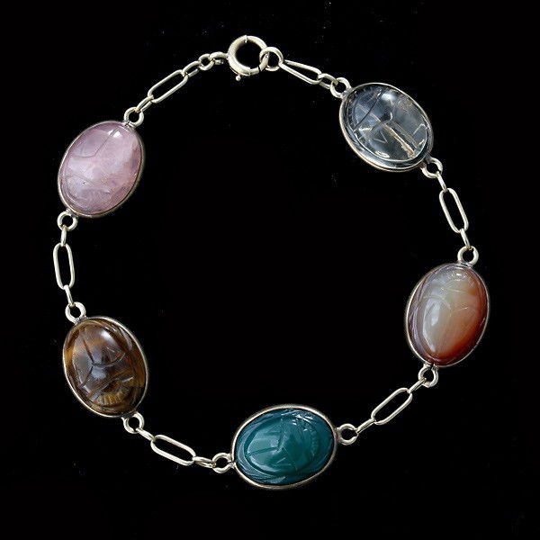 MULTI-STONE, CARVED SCARAB BRACELET.: MULTI-STONE, CARVED SCARAB BRACELET. Featuring five oval rose quartz, rock crystal quartz, agate, tiger's eye scarabs, measuring approximately 15x10 mm, bezel set in a 14k yellow gold articualted link