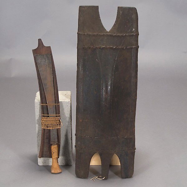 Philippine shield and Malaysian machete: BONTOC or Igorot PHILIPPINES shield and a Malaysian machete in sheath. Blackened wood, metal. Height of shield 36 3/8 inches. In good condition, sheath of machete partly split.