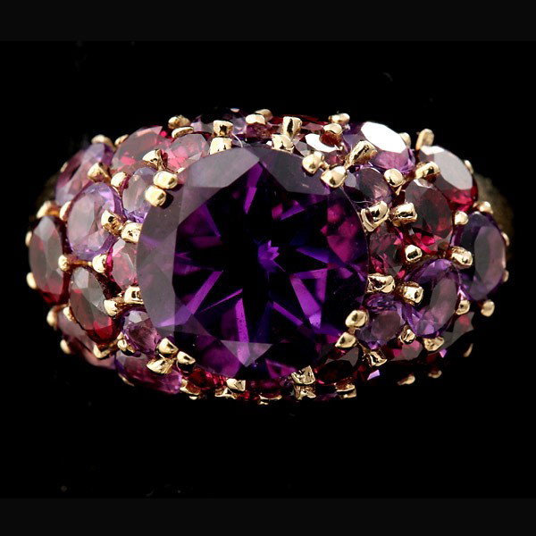 AMETHYST, GARNET, 10K YELLOW GOLD RING.: AMETHYST, GARNET, 10K YELLOW GOLD RING. Centering one round-cut amethyst weighing approximately 3.30 ct., accented by fifteen round-cut amethysts weighing a total of approximately 1.00 ct. and fifteen