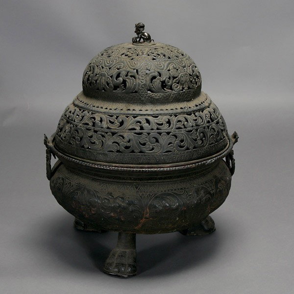 A Large Mongolian Cast Iron Censer: A Large Mongolian Cast Iron Censer, decorated with a stylized lotus motif, the reticulated domed cover topped by a lion finial, flanked by rings handles {Height: 25 1/2 inches} [Soiling, dents, overal