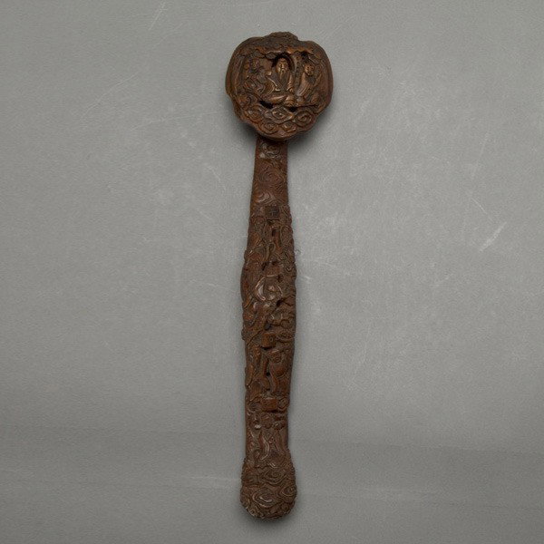 A Carved Wood Ruyi Scepter: A Carved Wood Ruyi Scepter, carved in relief with immortals and 'Qian Qiu Ru Yi' characters to the handle and head, surrounded by clouds and pine trees {Length: 14 inches} [Wear to the edges and under