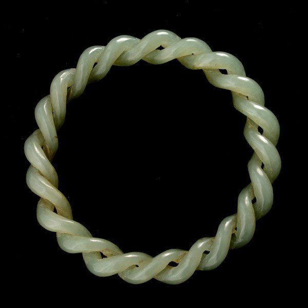 JADE BRACELET.: JADE BRACELET. The intricately carved two piece interlocking braided jadeite bangle measures approximately 10.00 mm in width and 57.00 mm internal diameter. {Note: Accompanied by box.}